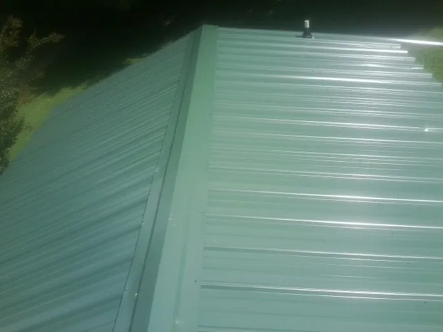 New green metal panels meeting at the ridge of a roof — Flat Roof Repair work by our crew in Federal Way