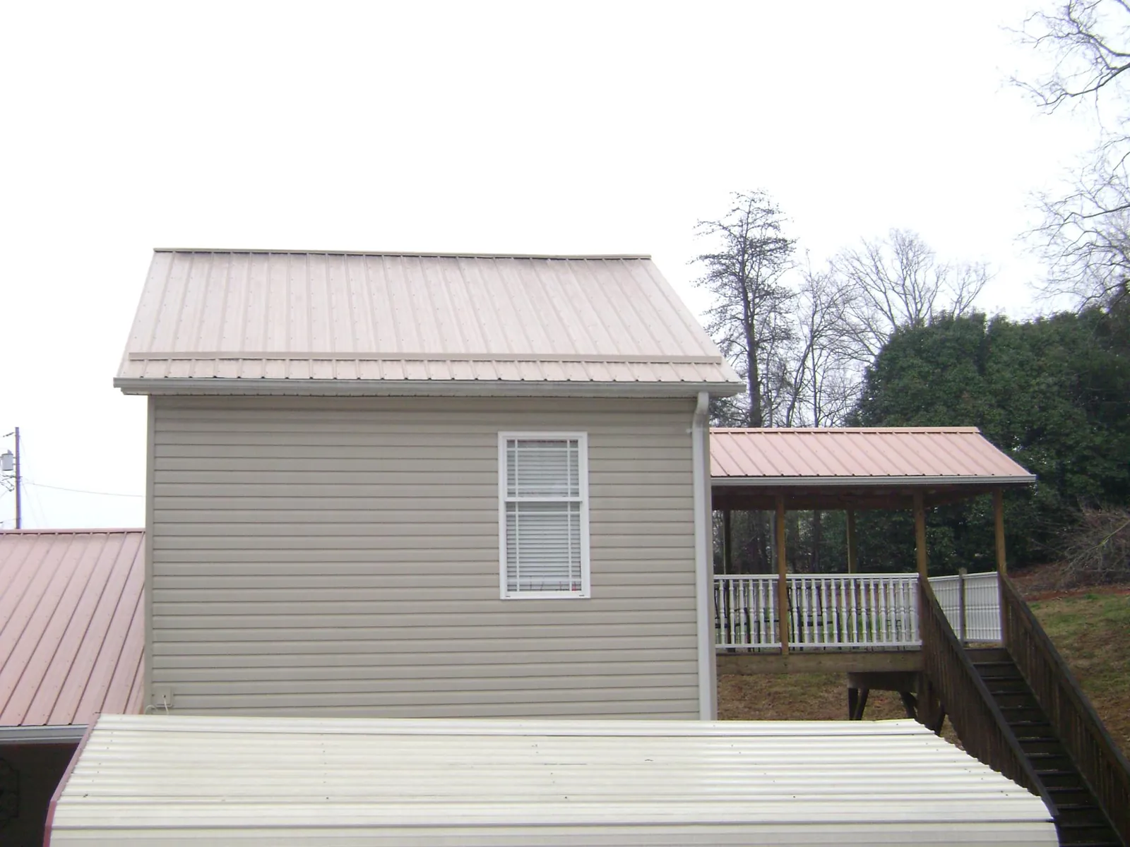 Tan metal roofs on a two story addition and attached porch, from a Roof Replacement job in Federal Way