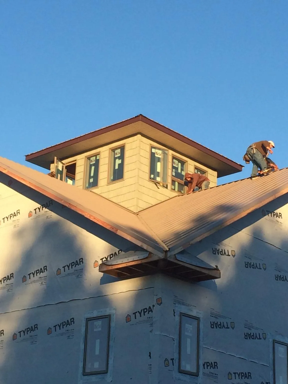 Roofers working around a rooftop cupola on a new metal roof at sunset — Roof Waterproofing in Federal Way by Roofing Brothers